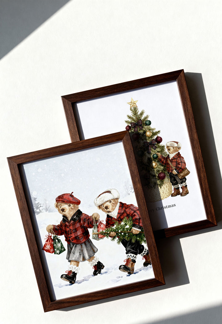Two framed prints of teddy bears by a Christmas tree on a white surface